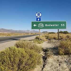 Road sign on side of desert road with direction to Badwater, Death Valley.