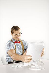 Caucasian young man dressed like nerd holding computer monitor in frustration.