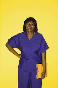 African-American mid-adult woman in medical uniform smiling holding chart.