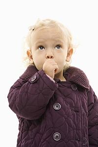 Young Caucasian female toddler wearing purple coat and sucking her thumb.