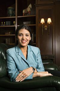 Prime adult Hispanic female sitting looking at viewer smiling.