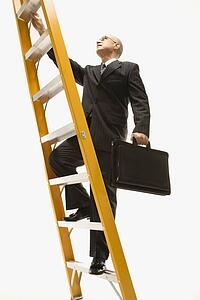 Caucasian middle-aged businessman climbing ladder carrying briefcase.