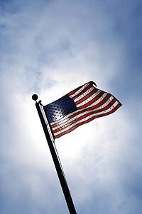 American flag blowing in breeze against blue sky.