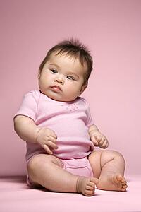 Asian baby sitting up and looking to side.