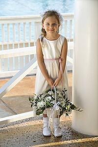 Portrait of Caucasian flower girl holding flower basket smiling.