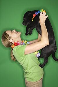 Caucasian prime adult female holding black puppy.