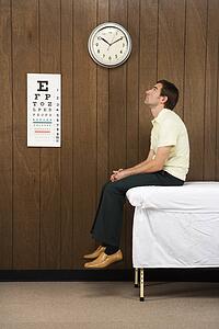 Caucasian mid-adult male waiting on table in retro doctor's office.
