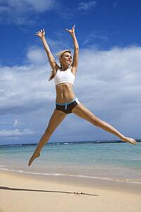 Caucasian young adult woman jumping on beach.