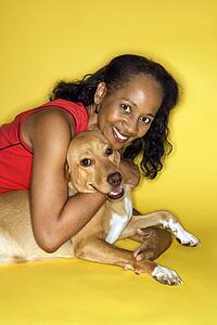 African American prime adult female hugging dog.