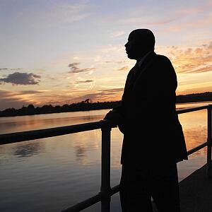 African-American man standing by water at sunset in Washington, D. C., USA.