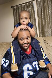 Portrait of African-American father with his son on his shoulders.