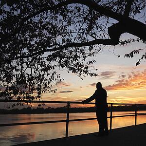 African-American man standing by water at sunset in Washington, D. C., USA.