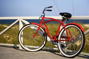 Red beach cruiser bicycle leaning against walkway rail on beach on Bald Head Island, North Carolina.