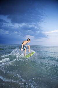 Caucasian male teen riding skimboard.