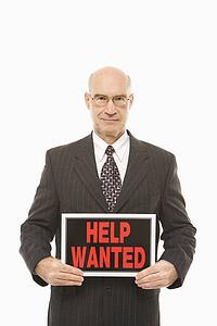 Caucasian middle-aged businessman holding help wanted sign.