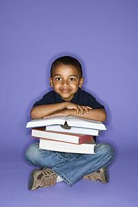 African American male child sitting with books.