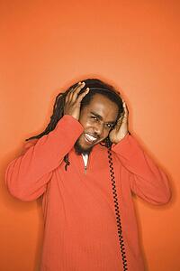 African-American mid-adult man listening to headphones wearing orange clothing on orange background.