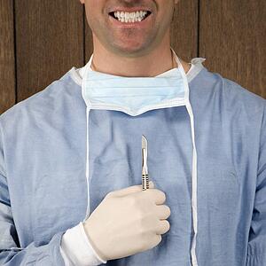 Mid-adult Caucasian male surgeon holding scalpel and smiling.