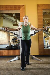 Prime adult Caucasian female using exercise equipment at gym.
