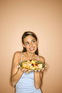 Portrait of young adult woman holding a plate of fruit.