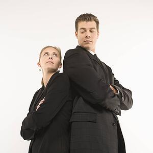 Caucasian mid-adult businessman and woman standing back to back looking at each other. 