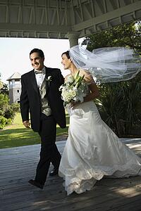 Caucasian mid-adult bride and groom walking together.