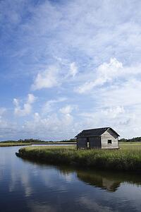 Weathered building in marsh on creek.