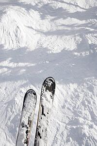 Skis dangling on top of trail drop.