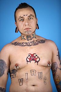 Barechested Caucasian mid-adult man with tattoos and piercings.