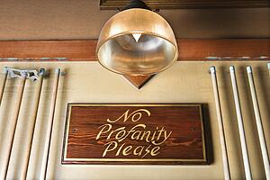 Low angle of sign in nightclub requesting no profanity.