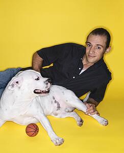 Young adult male Caucasian lying with white Pit Bull dog.