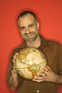 Portrait of smiling Caucasian man holding globe standing against orange background.