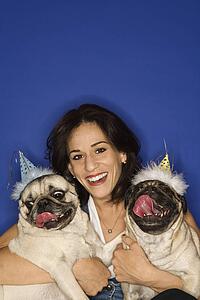 Caucasian prime adult female holding two Pug dogs.