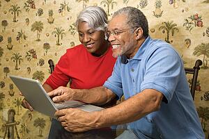 Portrait of mature African American couple looking at laptop in home. 