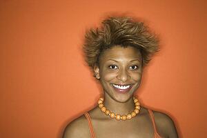 Portrait of smiling young African-American adult woman on orange background.