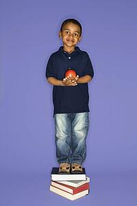African American male child standing on stack of books.