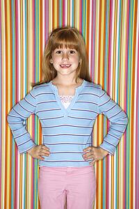 Caucasian female child looking at viewer with hands on hips.