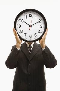 Caucasian middle-aged businessman holding clocks in front of their heads standing against white background.