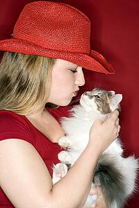 Young Caucasian female adult holding and kissing cat.