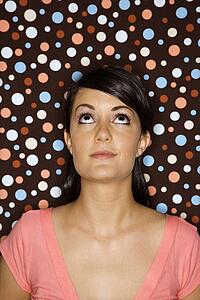 Young adult female Caucasian looking up on polka dot background.