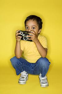 Hispanic male child kneeling with camera.
