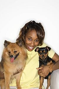 African American young adult female holding brown Pomeranian and Miniature Pinscher dogs.