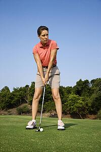 Caucasion mid-adult woman putting golf ball.