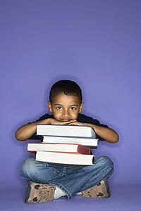 African American male child sitting with books.