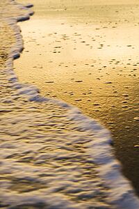 Waves lapping at beach at sunset.