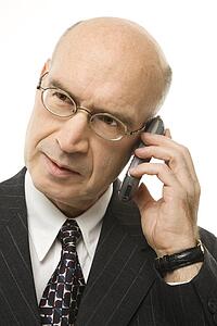 Caucasian middle-aged businessman on cellphone against white background.