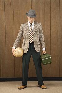 Mid-adult Caucasian male holding a globe and carrying luggage.