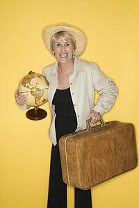 Caucasian mature adult female holding suitcase and globe.