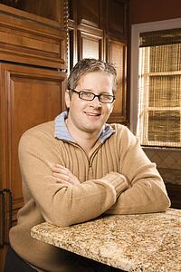 Caucasian man with arms crossed on kitchen counter.