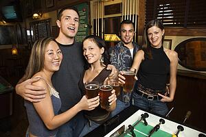 Portrait of group of young friends hanging out in pub and drinking beer.